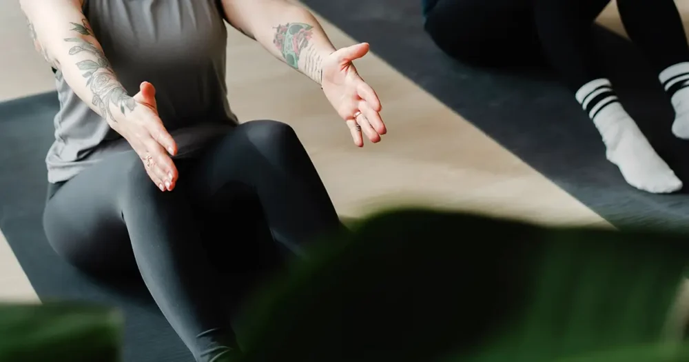 Pilatesohjaaja ohjaa osallistujia vahvistavaan pilatesharjoitukseen rauhallisessa studiossa.