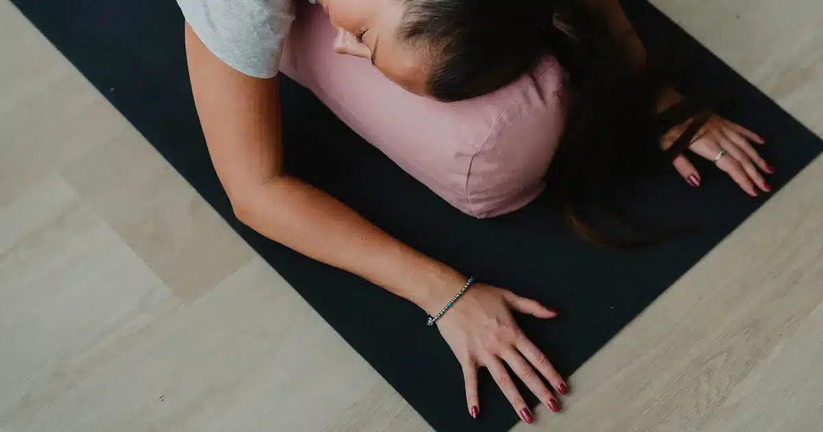 Joogaaja lepää rauhallisessa slow yin -asennossa valoisassa studiossa, jossa lämmin valo ja pehmeät sävyt tukevat syvää rentoutumista.