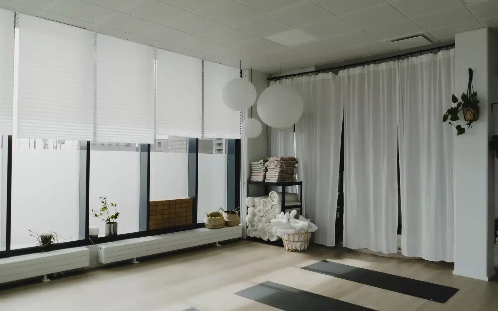 Valoisa joogasali, jossa suuret ikkunat ja valkoiset verhot, Barajoogan studio Kalasatamassa